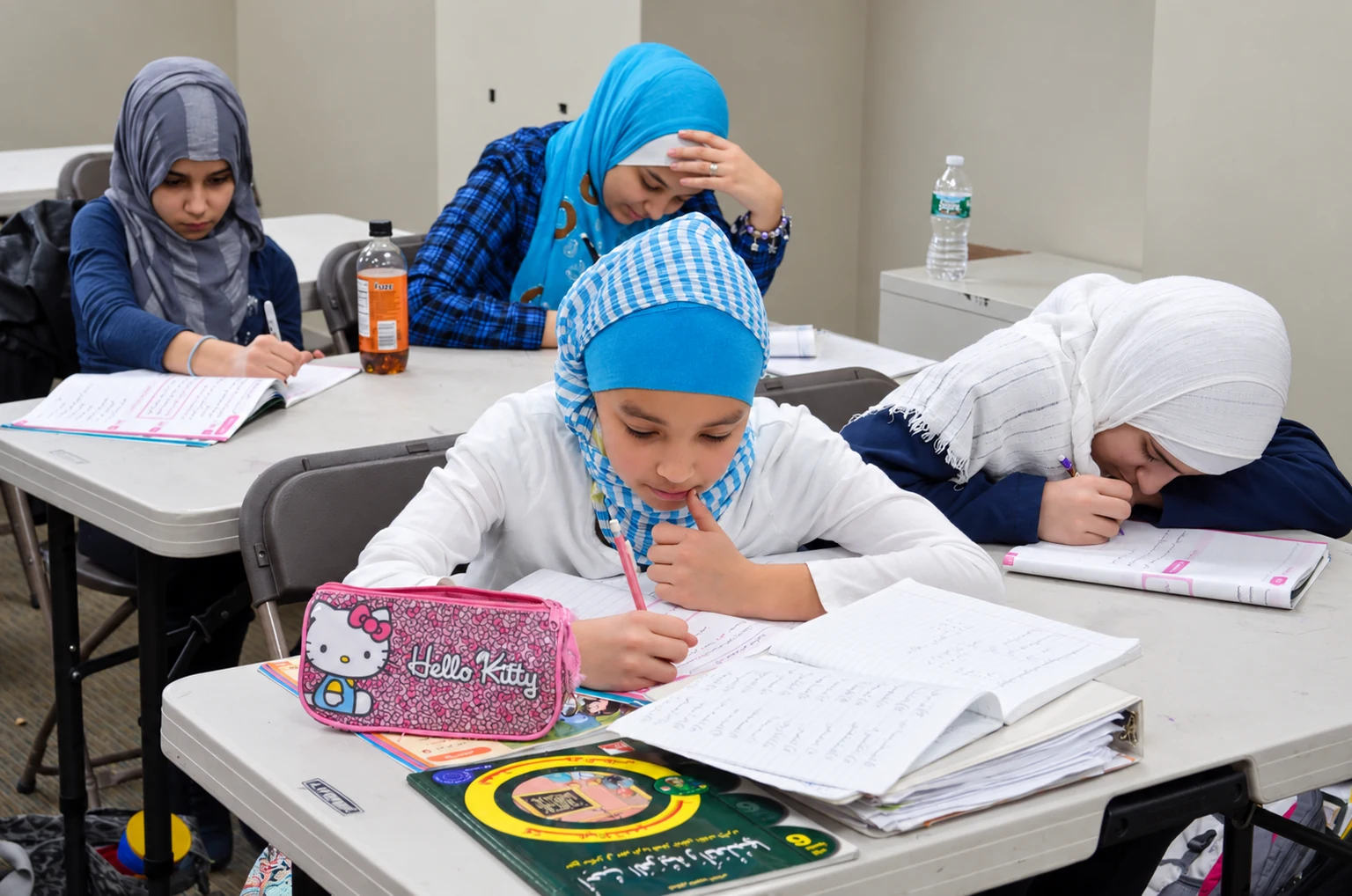 Four Al Huda students working on their lessons together at classroom desks.